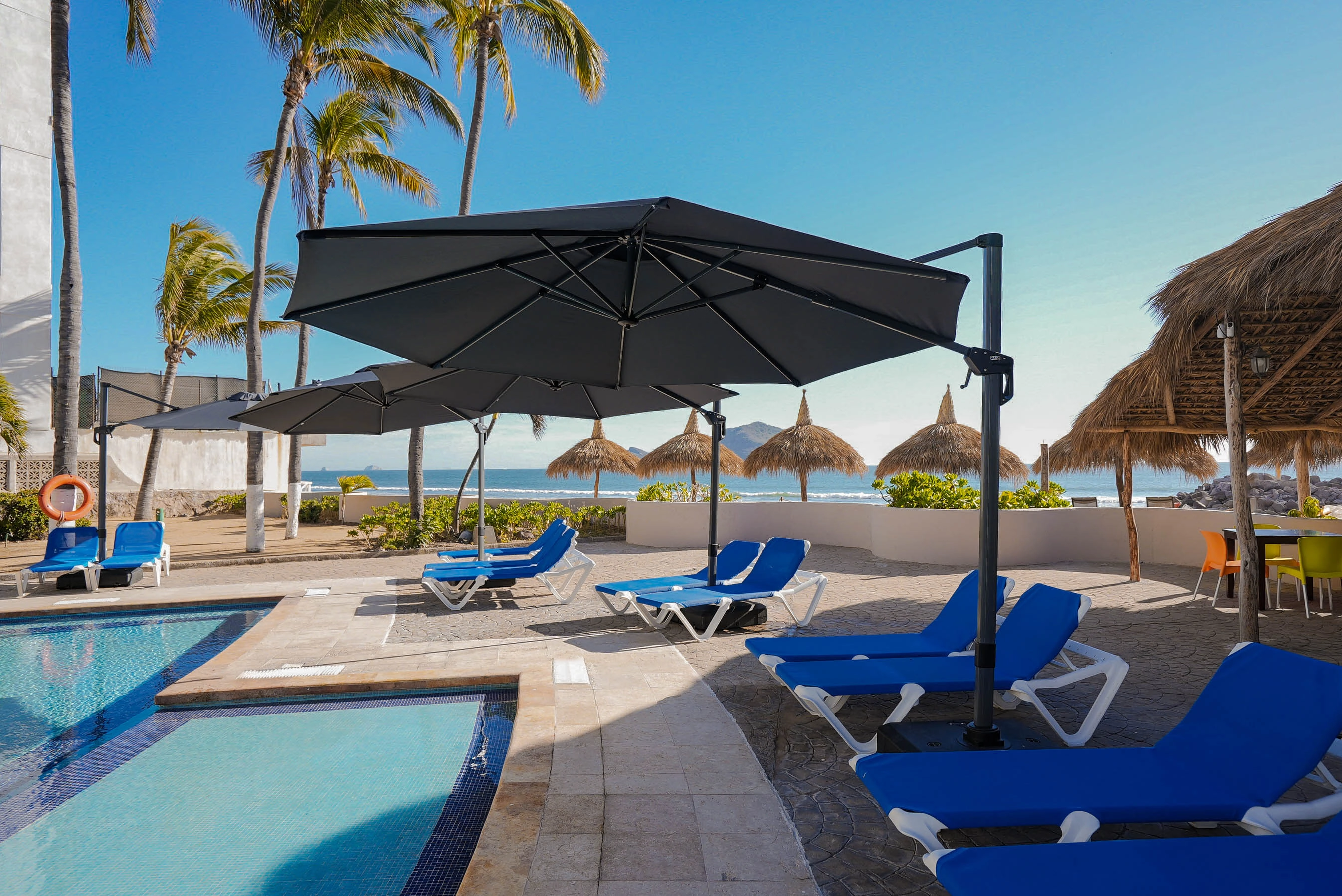 Vista lateral de alberca y camastros de Hotel Sunset Mazatlan